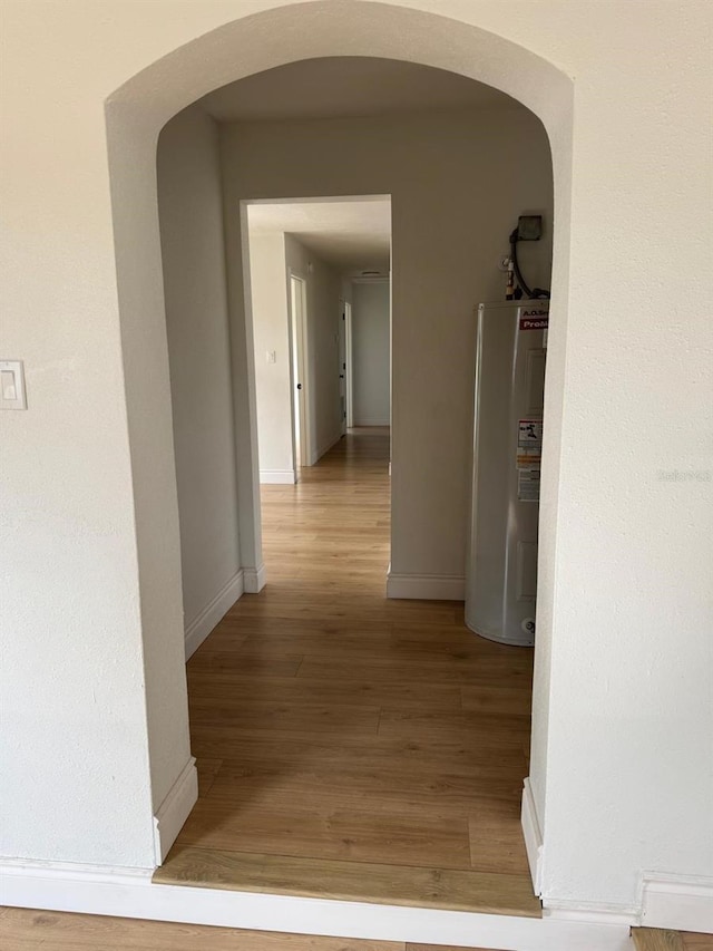 corridor with hardwood / wood-style floors and water heater