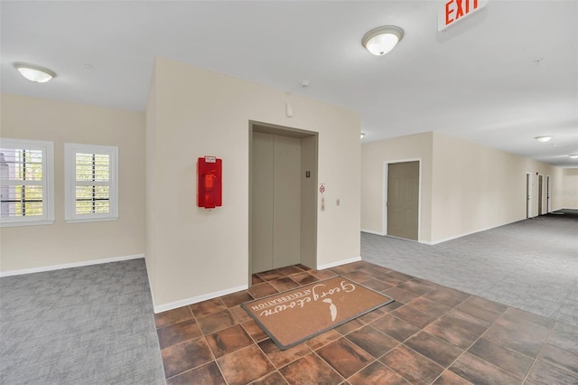 empty room featuring dark colored carpet and elevator