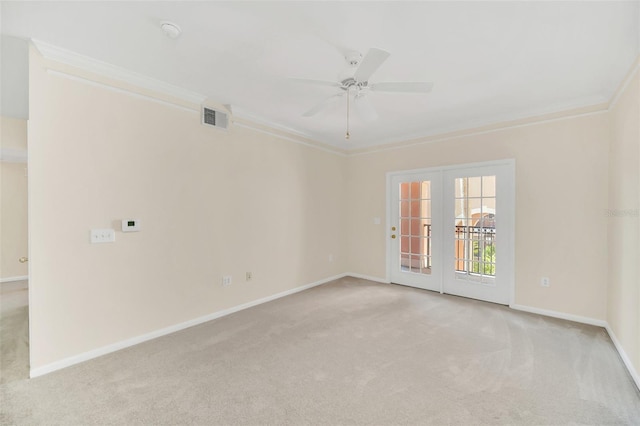 carpeted spare room with crown molding, ceiling fan, and french doors