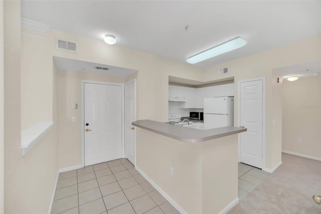 kitchen with sink, white cabinetry, light tile patterned floors, kitchen peninsula, and white fridge