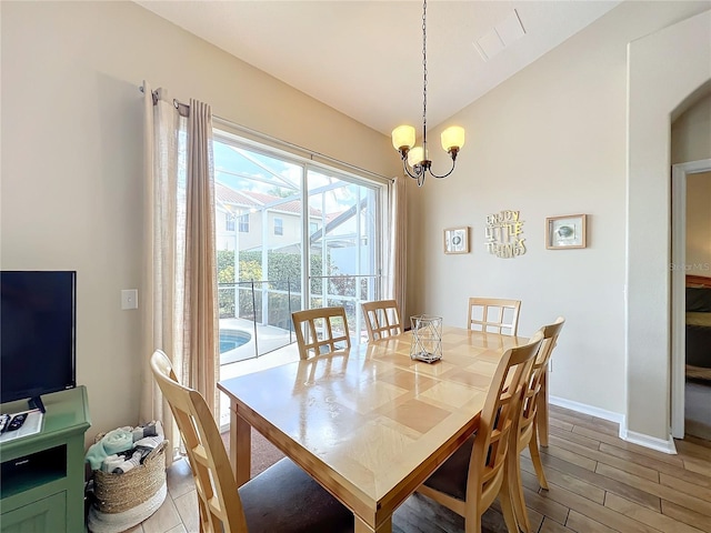 dining area with hardwood / wood-style flooring, vaulted ceiling, and a notable chandelier