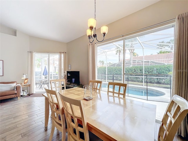 dining room featuring an inviting chandelier, wood-type flooring, and lofted ceiling