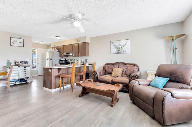 living room featuring ceiling fan, a textured ceiling, and light wood-type flooring