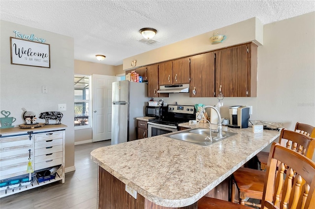 kitchen featuring stainless steel appliances, a kitchen breakfast bar, kitchen peninsula, and sink