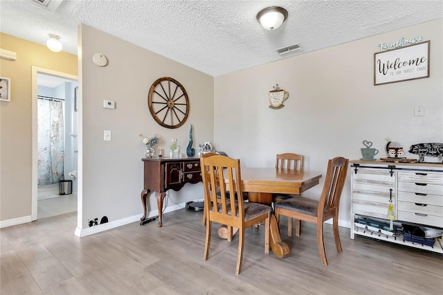 dining room featuring light hardwood / wood-style flooring and a textured ceiling