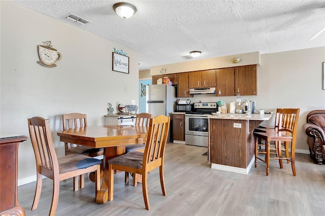 kitchen with a kitchen bar, light hardwood / wood-style flooring, sink, and appliances with stainless steel finishes