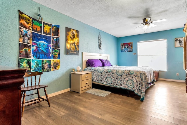 bedroom with ceiling fan, wood-type flooring, and a textured ceiling