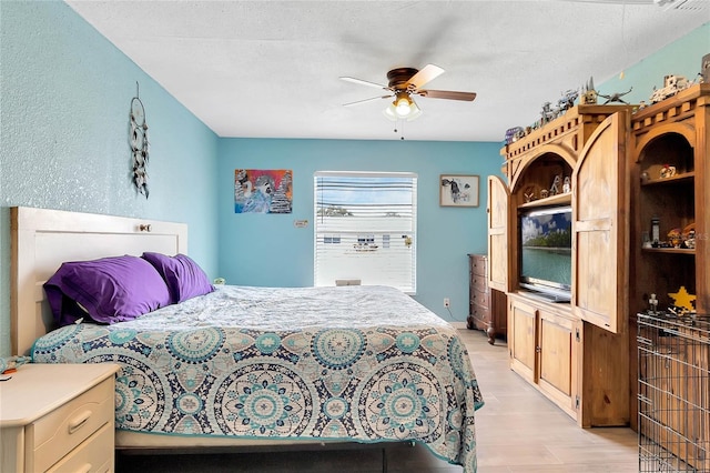 bedroom featuring a textured ceiling, ceiling fan, and light wood-type flooring