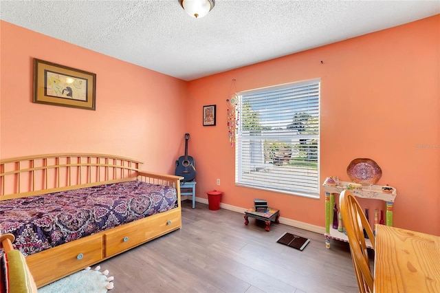 bedroom with hardwood / wood-style floors and a textured ceiling