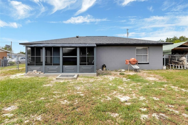 rear view of house with a sunroom and a lawn