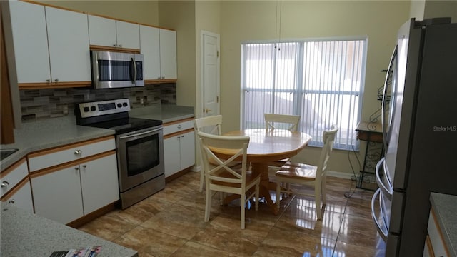 kitchen with stainless steel appliances, white cabinetry, and backsplash