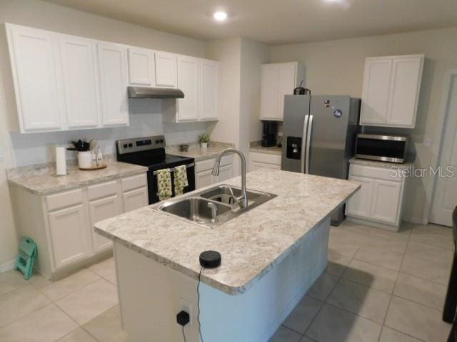 kitchen with sink, appliances with stainless steel finishes, an island with sink, light stone countertops, and white cabinets