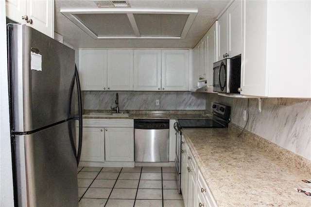 kitchen with appliances with stainless steel finishes, sink, light tile patterned floors, and white cabinets