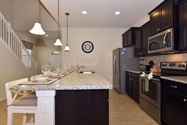 kitchen with appliances with stainless steel finishes, sink, a kitchen breakfast bar, hanging light fixtures, and a center island with sink