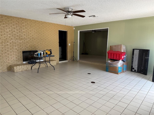 interior space featuring brick wall, light tile patterned floors, a textured ceiling, and a fireplace