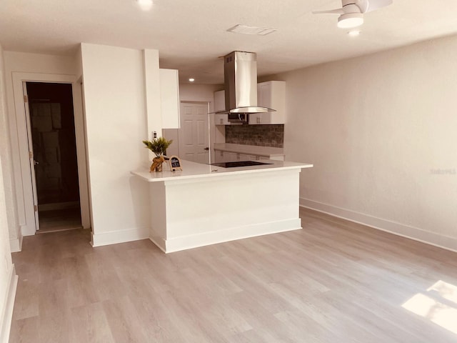 kitchen featuring light hardwood / wood-style flooring, backsplash, white cabinets, island exhaust hood, and kitchen peninsula