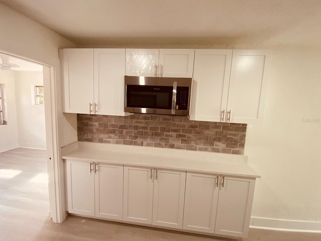 kitchen featuring white cabinetry, light wood-type flooring, and backsplash