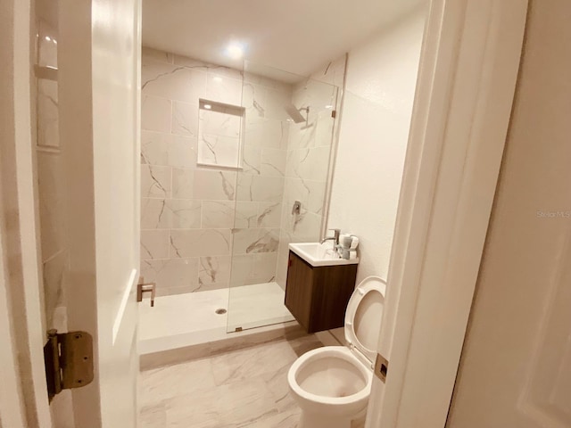 bathroom with vanity, toilet, and tiled shower