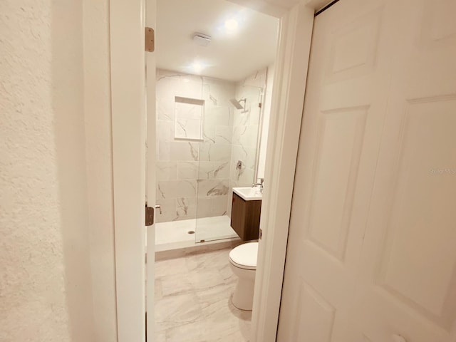 bathroom featuring vanity, a shower with shower door, and toilet