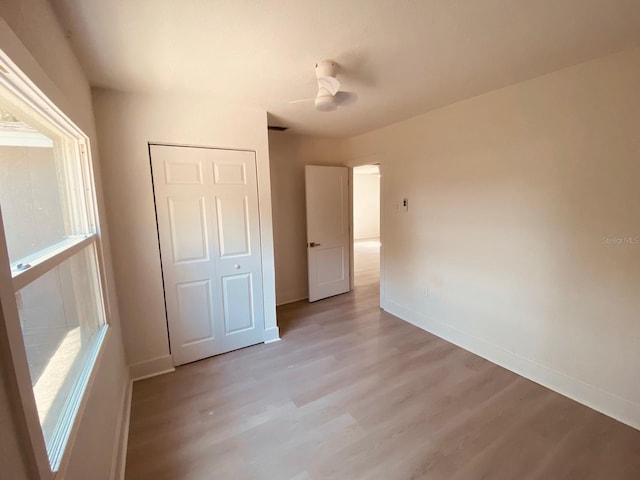 unfurnished bedroom with ceiling fan, a closet, and light hardwood / wood-style flooring