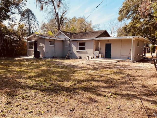 rear view of house featuring cooling unit and a lawn