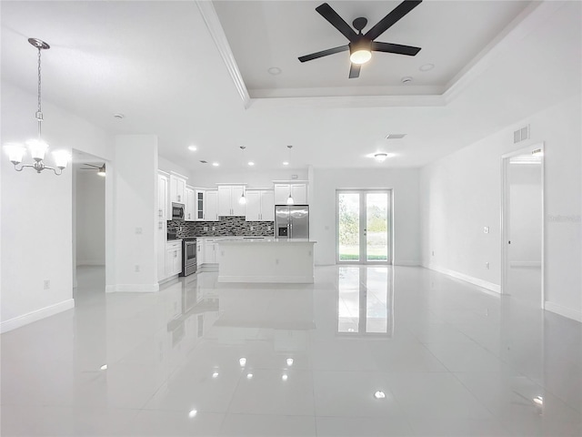 unfurnished living room with a tray ceiling and ceiling fan with notable chandelier