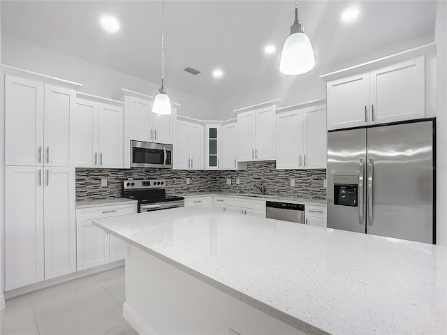 kitchen featuring pendant lighting, light stone counters, stainless steel appliances, and white cabinetry