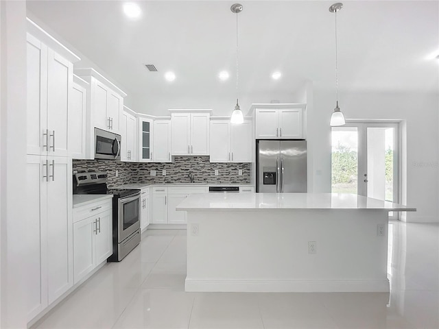 kitchen featuring white cabinetry, decorative light fixtures, a center island, and appliances with stainless steel finishes