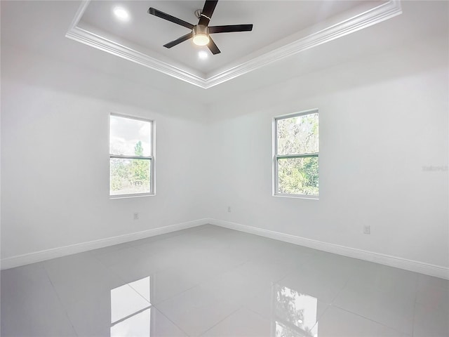 empty room with crown molding, ceiling fan, plenty of natural light, and a raised ceiling