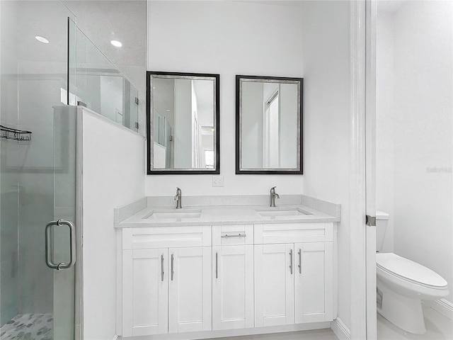 bathroom with vanity, a shower with shower door, and toilet