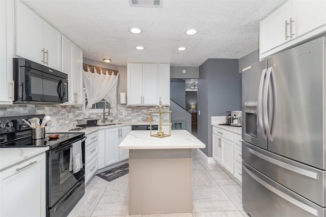 kitchen featuring white cabinetry, sink, a center island, light stone counters, and black appliances