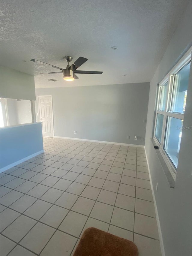 spare room with ceiling fan, a textured ceiling, and light tile patterned floors