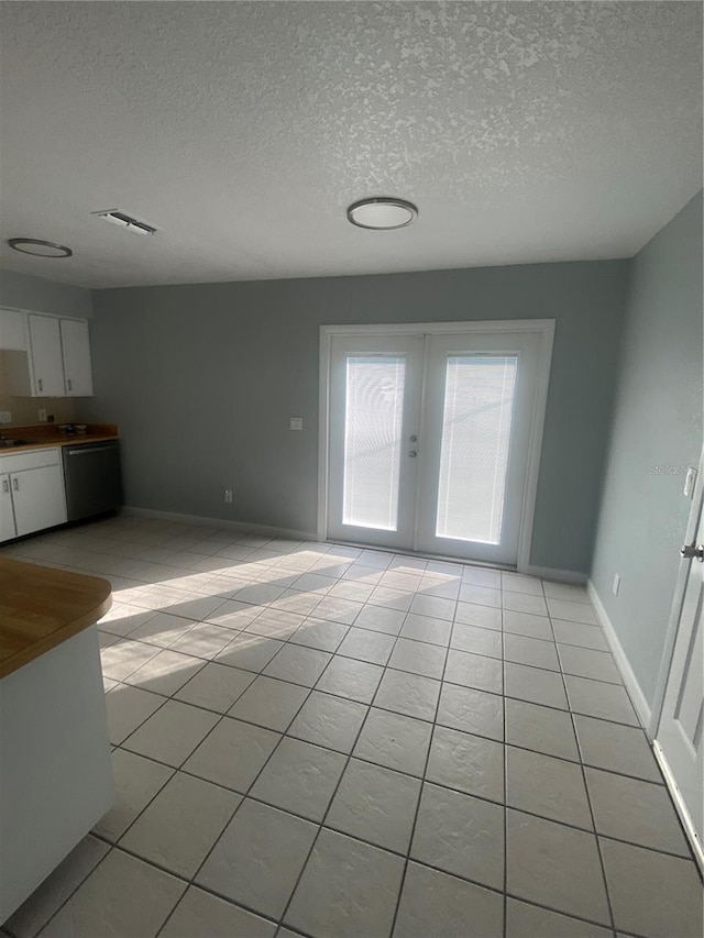 unfurnished living room with french doors, light tile patterned flooring, sink, and a textured ceiling