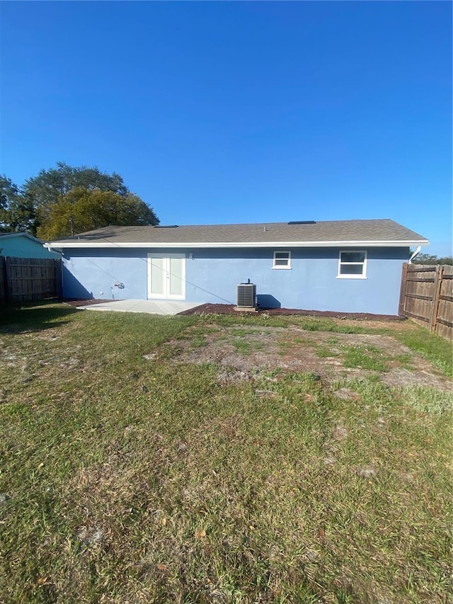 back of property with a yard and central AC