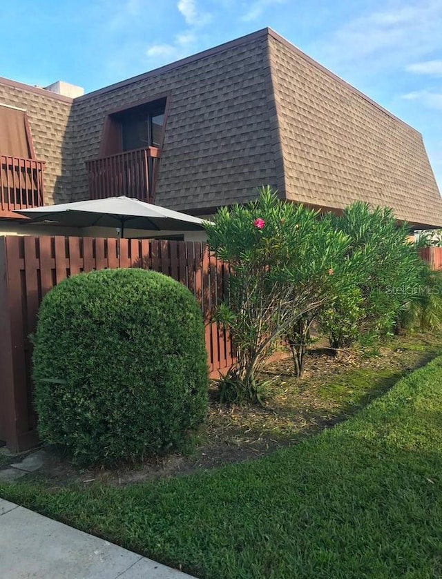 view of side of property featuring a lawn and a balcony