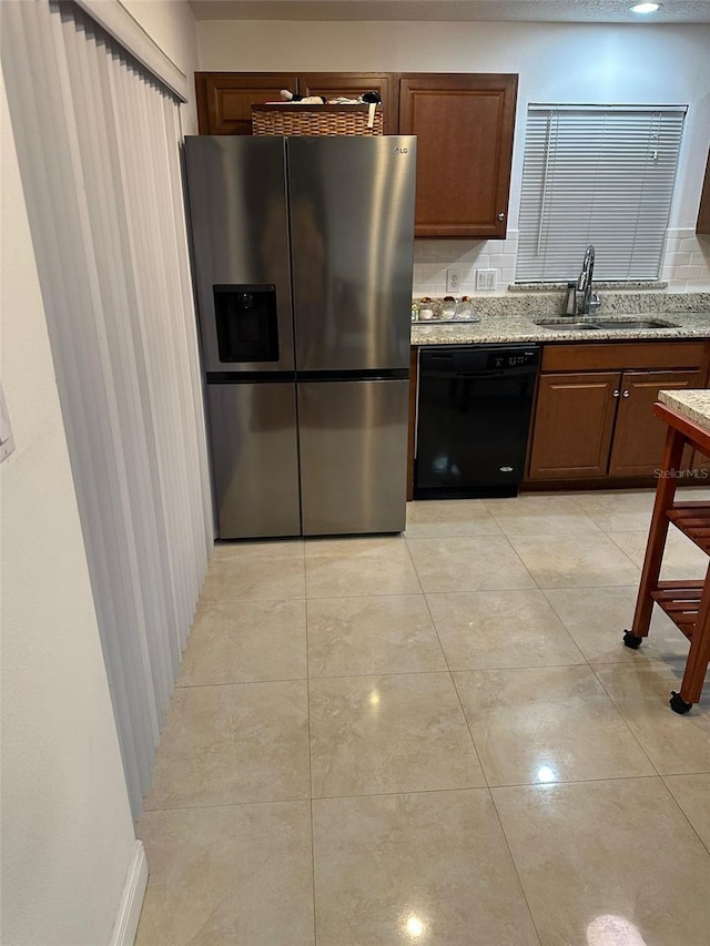 kitchen with dishwasher, light stone countertops, sink, and stainless steel fridge with ice dispenser