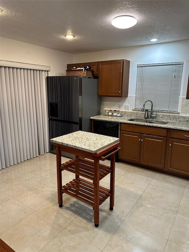 kitchen with sink, backsplash, black appliances, and light stone countertops