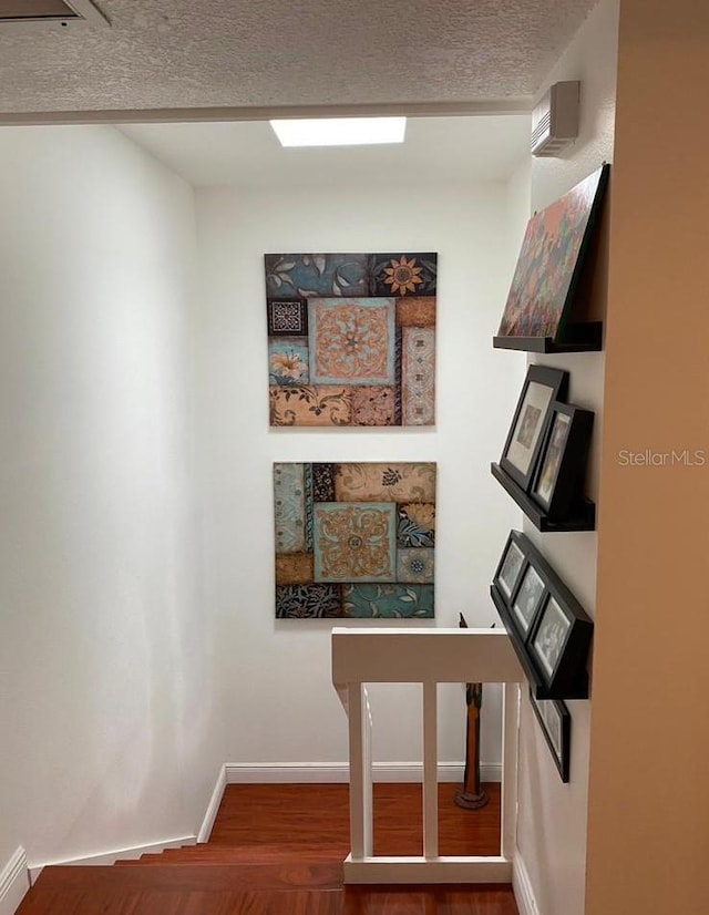 stairs featuring hardwood / wood-style flooring and a textured ceiling