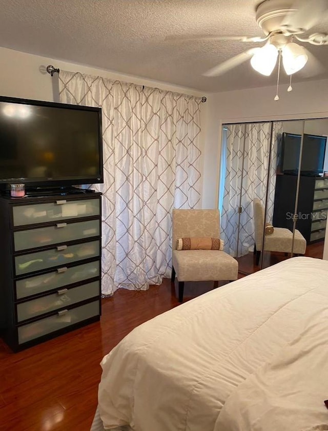 bedroom with dark wood-type flooring, ceiling fan, and a textured ceiling