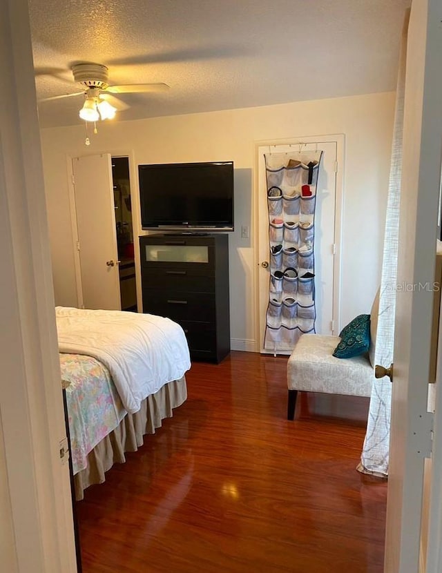 bedroom with ceiling fan, a textured ceiling, and dark hardwood / wood-style flooring