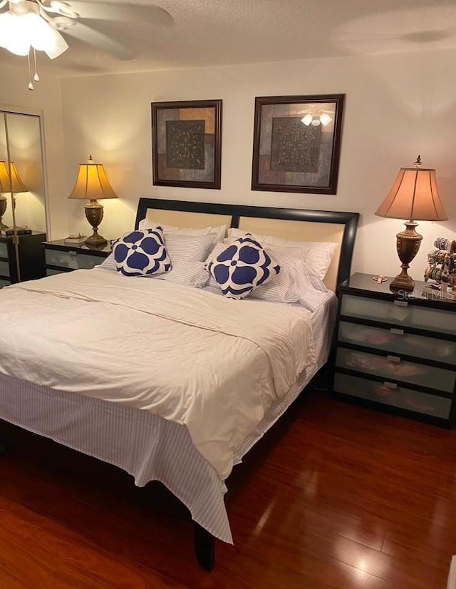 bedroom featuring dark wood-type flooring, a textured ceiling, and ceiling fan