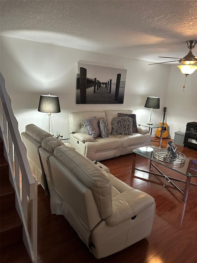 living room with ceiling fan, a textured ceiling, and dark hardwood / wood-style flooring