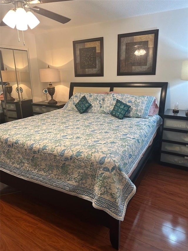 bedroom featuring dark wood-type flooring, a closet, and ceiling fan