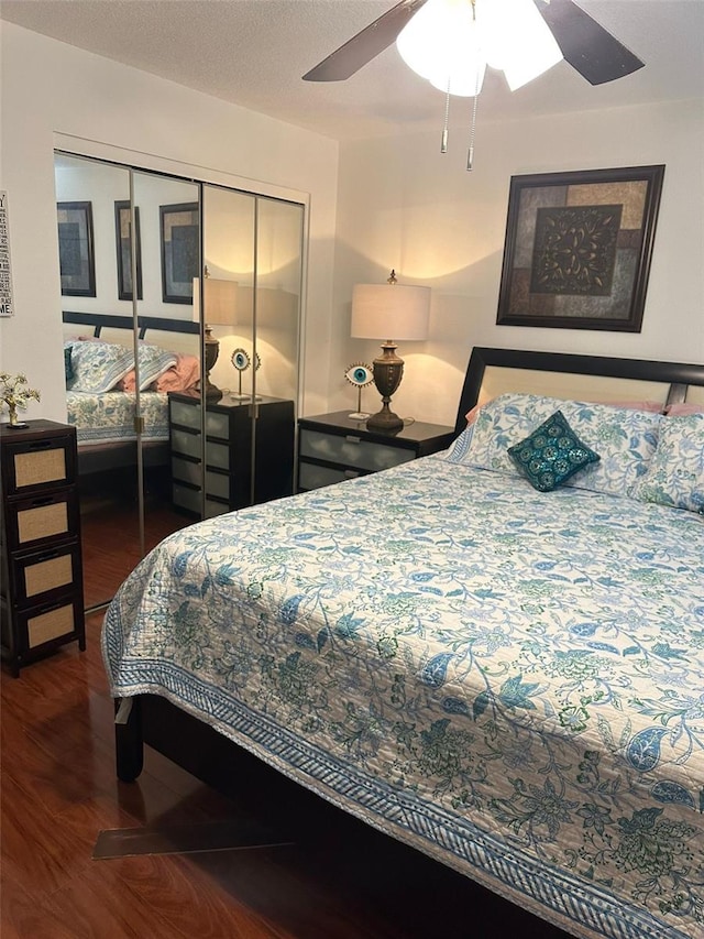 bedroom with a textured ceiling, dark wood-type flooring, a closet, and ceiling fan