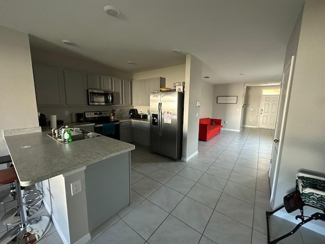 kitchen with stainless steel appliances, sink, gray cabinetry, and kitchen peninsula