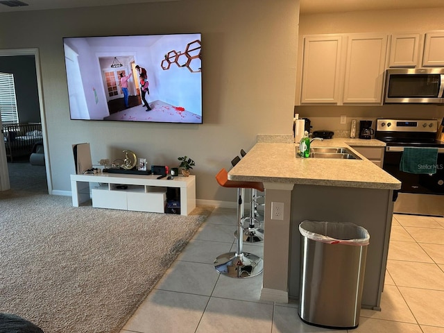 kitchen featuring appliances with stainless steel finishes, light tile patterned floors, white cabinets, and kitchen peninsula