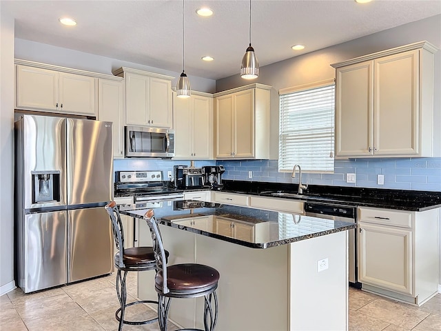 kitchen featuring sink, a center island, pendant lighting, stainless steel appliances, and cream cabinetry