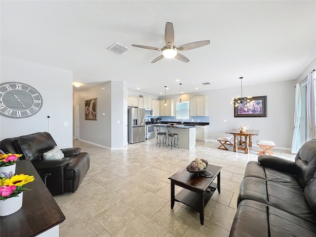 3857 San Isidro Cir, Saint Cloud, FL 34772 - living room featuring sink, ceiling fan with notable chandelier, and a textured ceiling