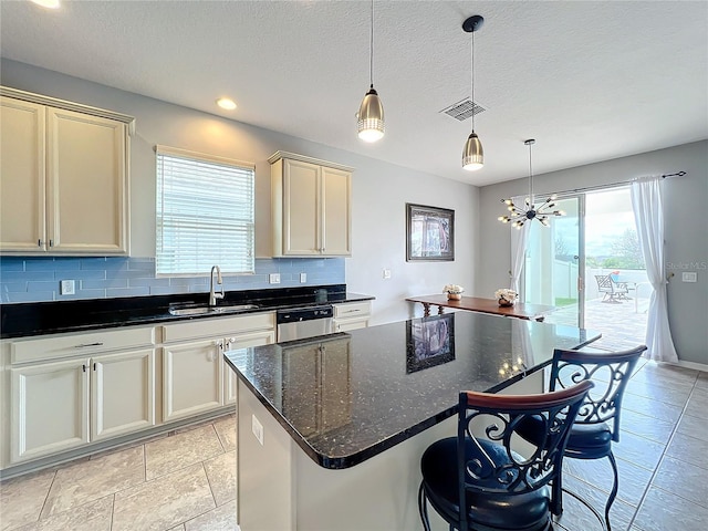3857 San Isidro Cir, Saint Cloud, FL 34772 - kitchen with sink, tasteful backsplash, decorative light fixtures, dark stone countertops, and a kitchen island