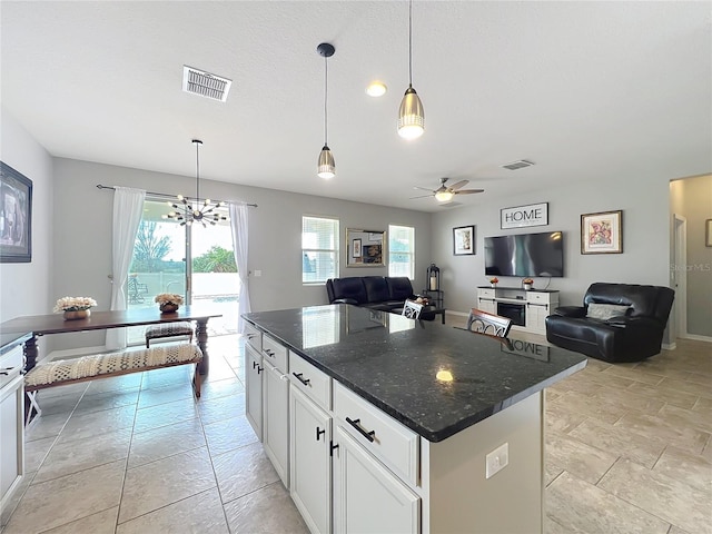 3857 San Isidro Cir, Saint Cloud, FL 34772 - kitchen with dark stone countertops, hanging light fixtures, white cabinets, and a kitchen island
